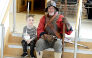 Boy with toy sword sat next to soldier in the national civil war centre